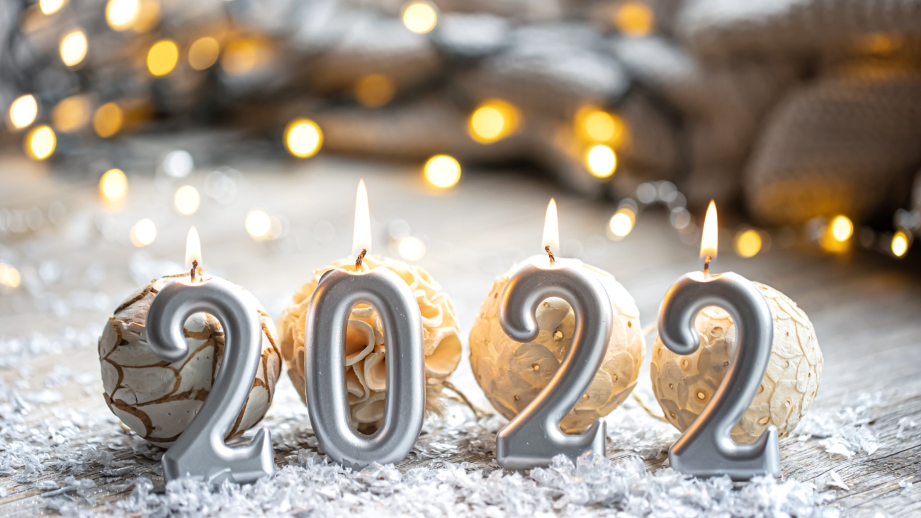 Festive Christmas background with burning candles in the form of the numbers 2022 on a blurred background with bokeh.