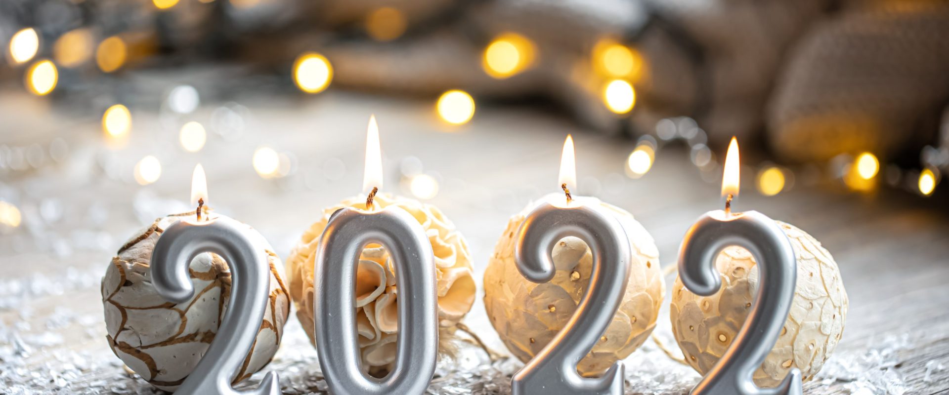 Festive Christmas background with burning candles in the form of the numbers 2022 on a blurred background with bokeh.